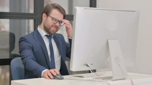 Stressed Businessman Working at Computer in Office