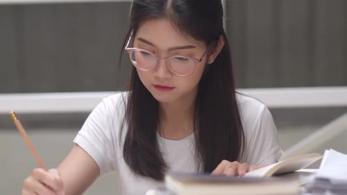 Asian student women reading books in library at university.