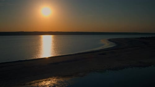 Soleil doré se reflétant sur la surface de l'eau de mer, vue aérienne, plage de sable au lever du soleil