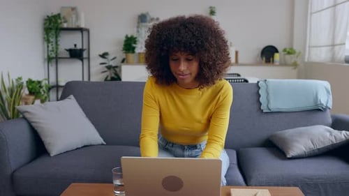 Woman Using Laptop on Couch in Home