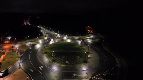 Aerial orbit shot of roundabout lighting at night. Traffic scene in american town. Top down shot.