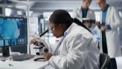 Mulher trabalhando com microscópio e bandeja de amostra no laboratório de química