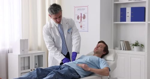 Urologist in protective gloves examining patient on medical couch in clinic