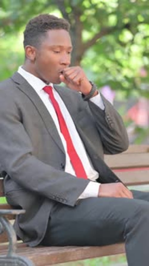 Young man in suit sitting on park bench