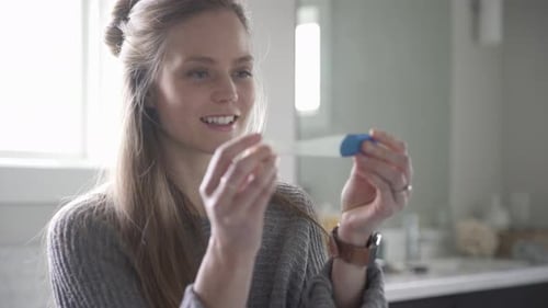 Woman holding pregnancy test in bright bathroom