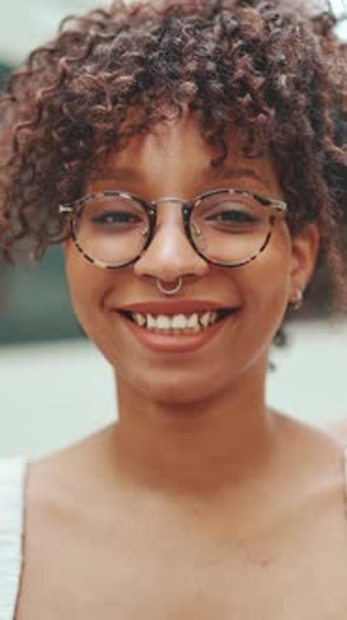 Close-up portrait of a young woman in glasses smiling while looking at the camera