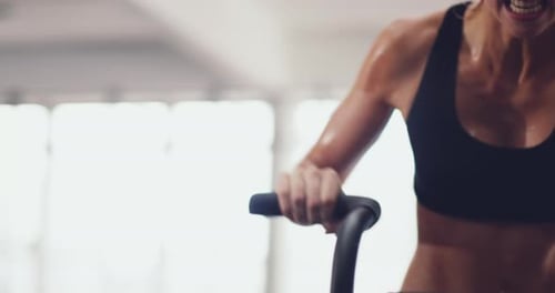 Athletic, fit and active woman sweating at the gym while cycling on an exercise bike