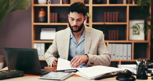 Man Writes at Office Desk With Laptop