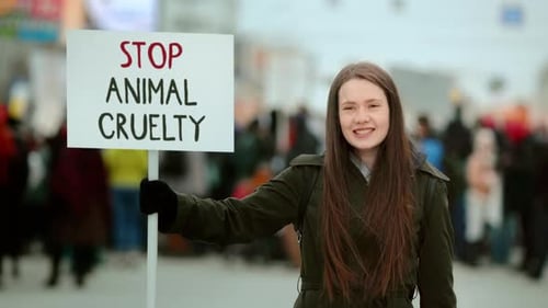 Une fille tient une bannière Stop à la cruauté envers les animaux lors d'une manifestation végétalienne