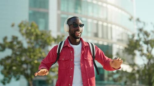 Happy Young African Man in Headphones Listening Music Dancing on City Street