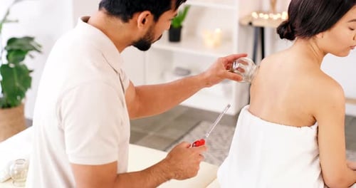 Man Performing Cupping Treatment on Woman in Spa