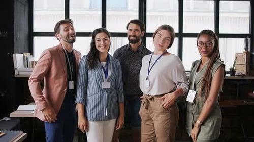 Portrait of Young Businesspeople Standing Indoors in Office, Looking at Camera