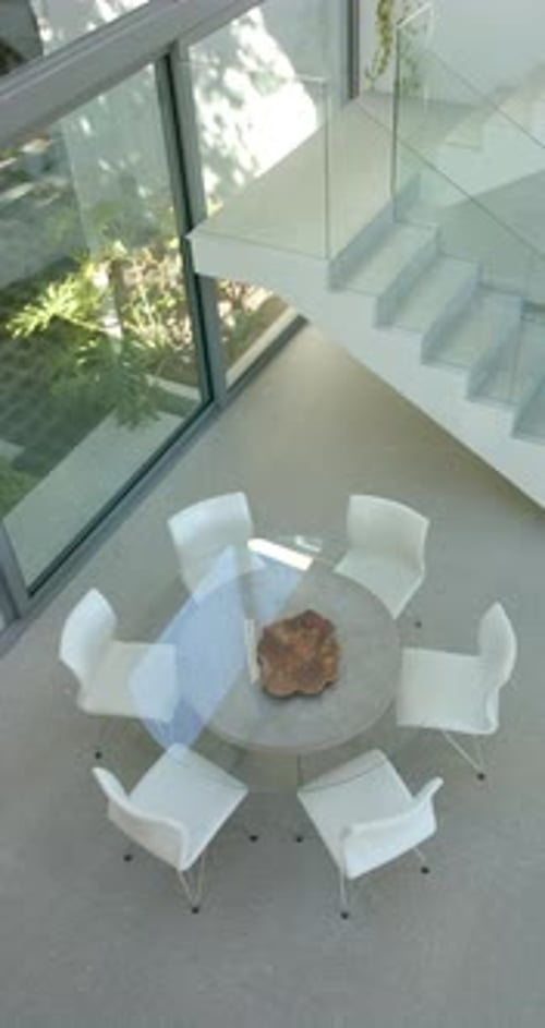 Vertical video: Modern dining area with glass table and white chairs in bright home