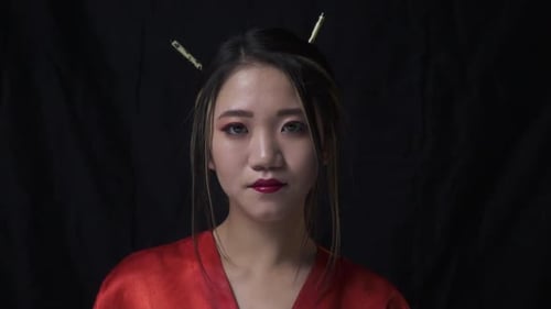 Woman in Red Silk Robe Against Black Background