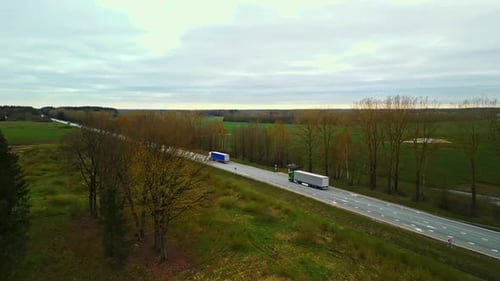 A Vehicle on Asphalt Road Crossing Grasslands Under Cloudy Sky