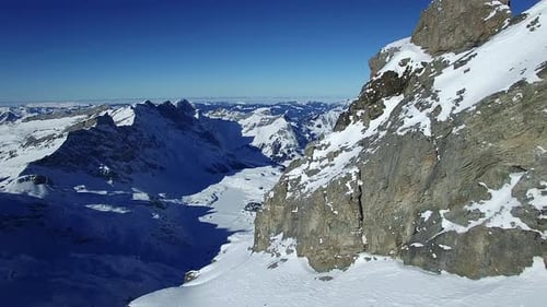 Snowcovered Alpine Mountain Ridge Under Clear Blue Sky Perfect for Exploring Pristine Wilderness