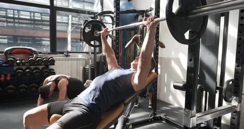 Man Doing Bench Press in a Gym