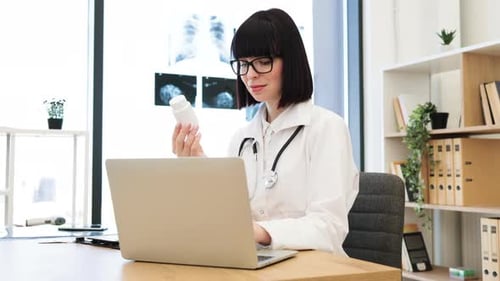 Doctor Working at Laptop in Bright Office