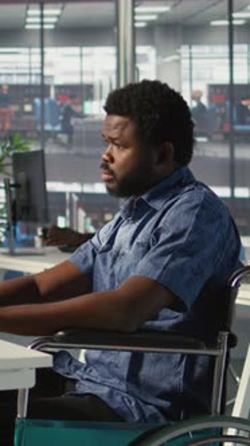 Man in Wheelchair Working at Desk in Office