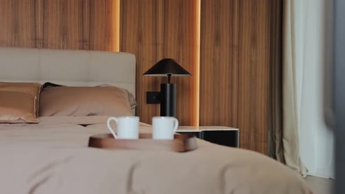 Closeup Cozy Bedroom with Silk Cream Bedding Nightstand Lamp and Coffee Cups on the Bed Great for