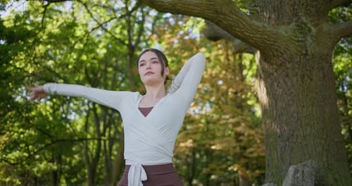 Young Beautiful Athletic Woman in Sportswear Doing Stretching and Warming Up in the Park Near a Tree