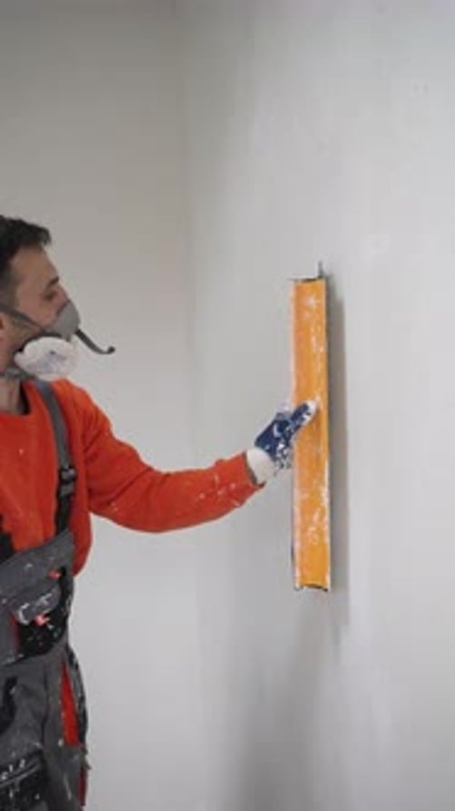 Man Smoothing Plaster on Interior Wall with Tool