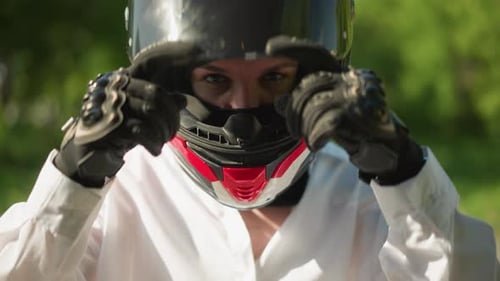 CloseUp of Female Biker in White Shirt Closing Helmet Visor Green Background