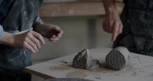 Child's Hands Working with Clay While Boy Learning Pottery in Studio with Grandfather