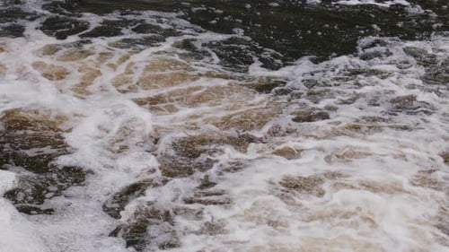 Detailed surface view of foamy swirling river water, full of motion and texture