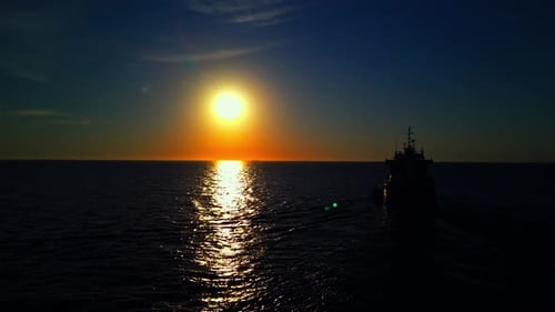Aerial Footage of a Ship Sailing Gracefully Into the Serene Sunset Over the Calm Waters of the Ocean