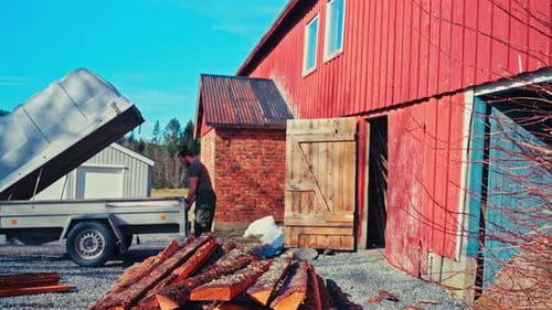 Man Unloading Wood Outside of a Rustic Barn