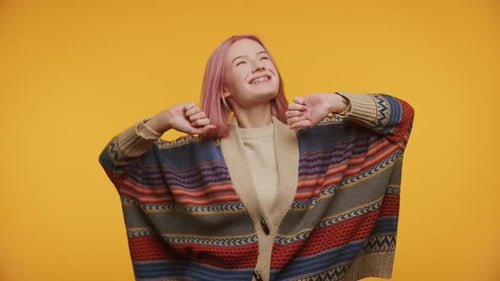 Joyful teen celebrates with arms raised on yellow