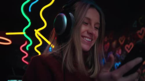 Blonde Woman Listens to Music on Phone at Night