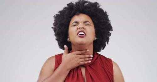 A young woman coughing against a grey background