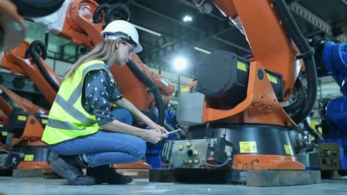 Technikerin inspiziert und repariert den Roboterarm im Roboter-Hangar und testet den Betrieb