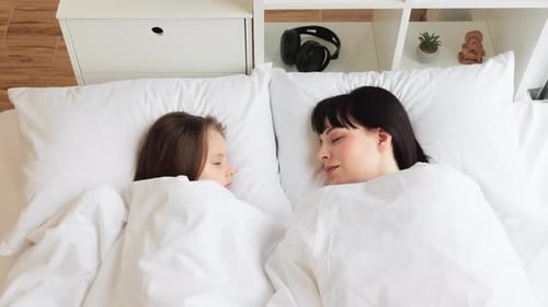 Mother and Daughter Sleeping Peacefully in Bed