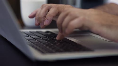 Hands Typing on Laptop Keyboard in Office Setting