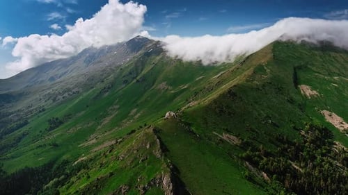 Beautiful mountain landscape with clouds and sun in a canyon. Drone shot of green mountains with clo