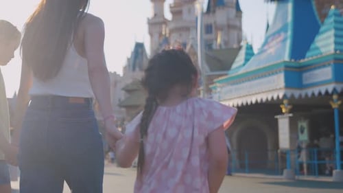 Asian mother and adorable kid daughters walking at the theme park.