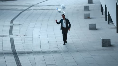 Disappointed businessman throws documents then walks confidently down the street