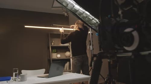 Light Engineer Installing Lamp Above Presenters Table in Studio