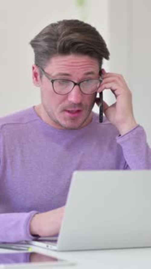 Man Talking on Phone While Using Laptop Computer
