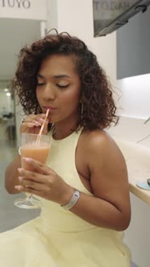 Woman in Yellow Dress Drinks Juice with Straw