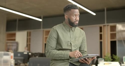 Portrait of Afro American entrepreneur in office working on digital tablet
