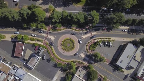 Aerial Of Busy Roundabout In Suburbs With Vehicles Circling On A Sunny Day