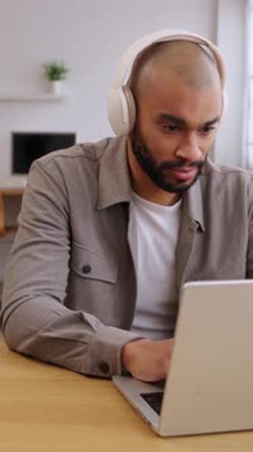 Man With Headphones Works on Laptop at Desk