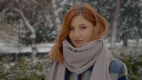 Redhead woman enjoying a snowy day in the park with a warm scarf
