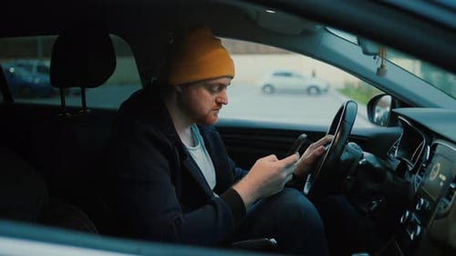 Man Using Phone in Car on City Street