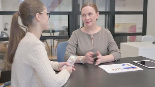 Woman Receives Cash from Young Adult in Office