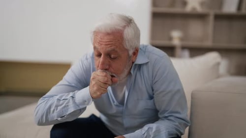 Un hombre mayor que se siente mal tiene una tos terrible, anciano de pelo gris, que sufre de asma, tos